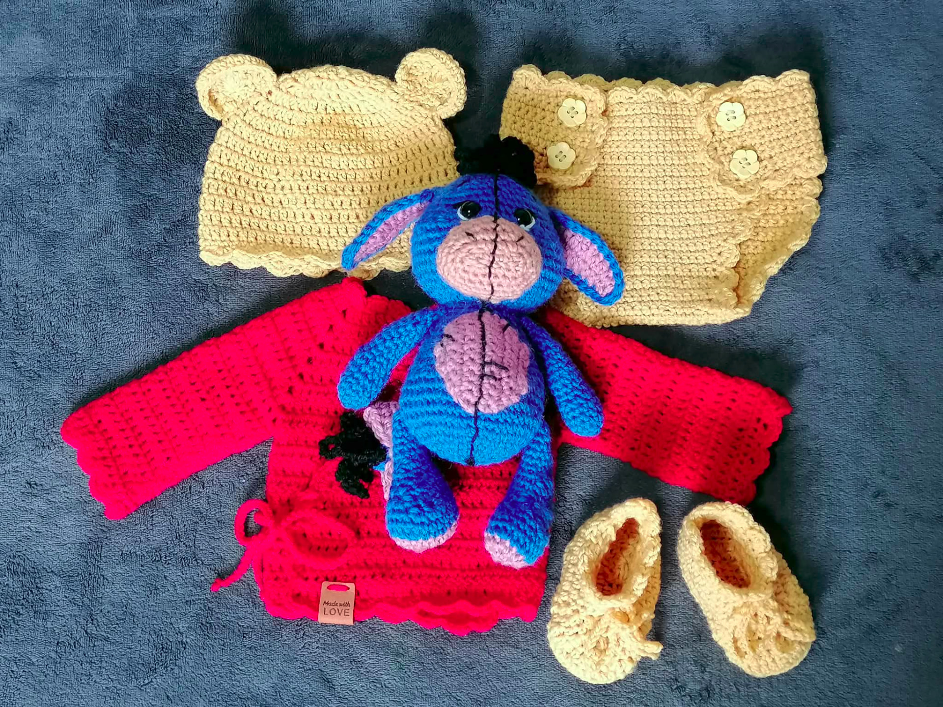 Handmade crocheted baby clothing set with a blue and pink character