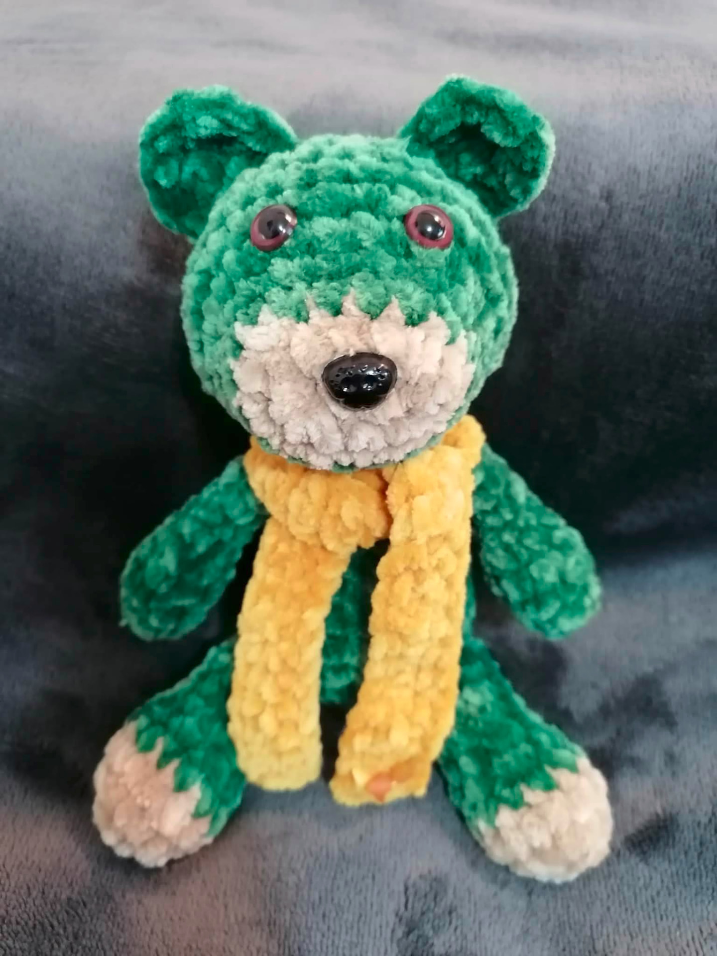 Handmade crocheted green teddy bear with a yellow scarf and cream muzzle