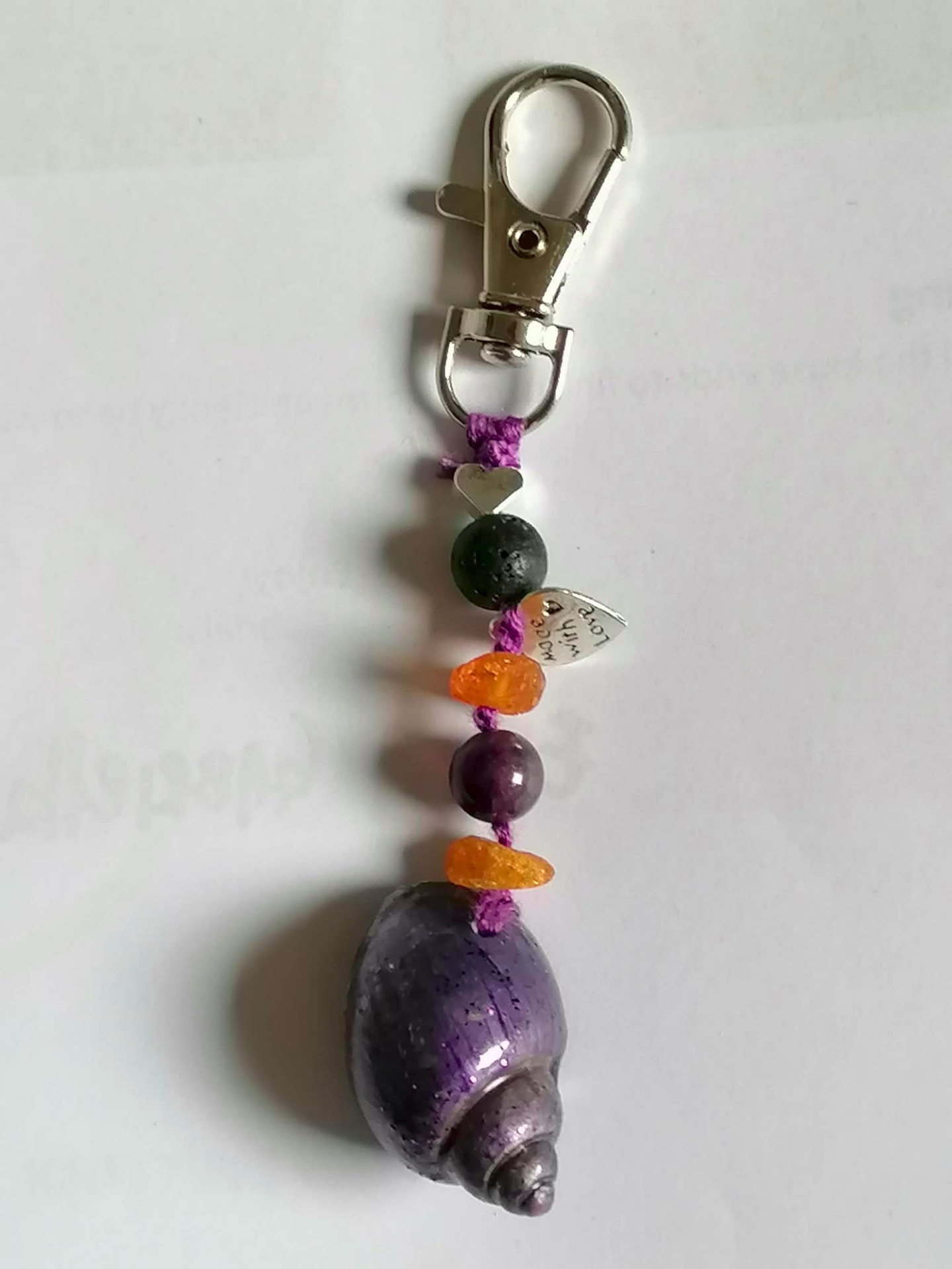 A handmade keepsake charm with natural stones, a purple shell and a metal heart